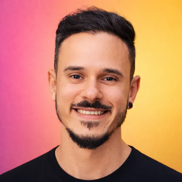 Retrato de Marcos Jr. sorrindo, com fundo em degradê rosa e amarelo